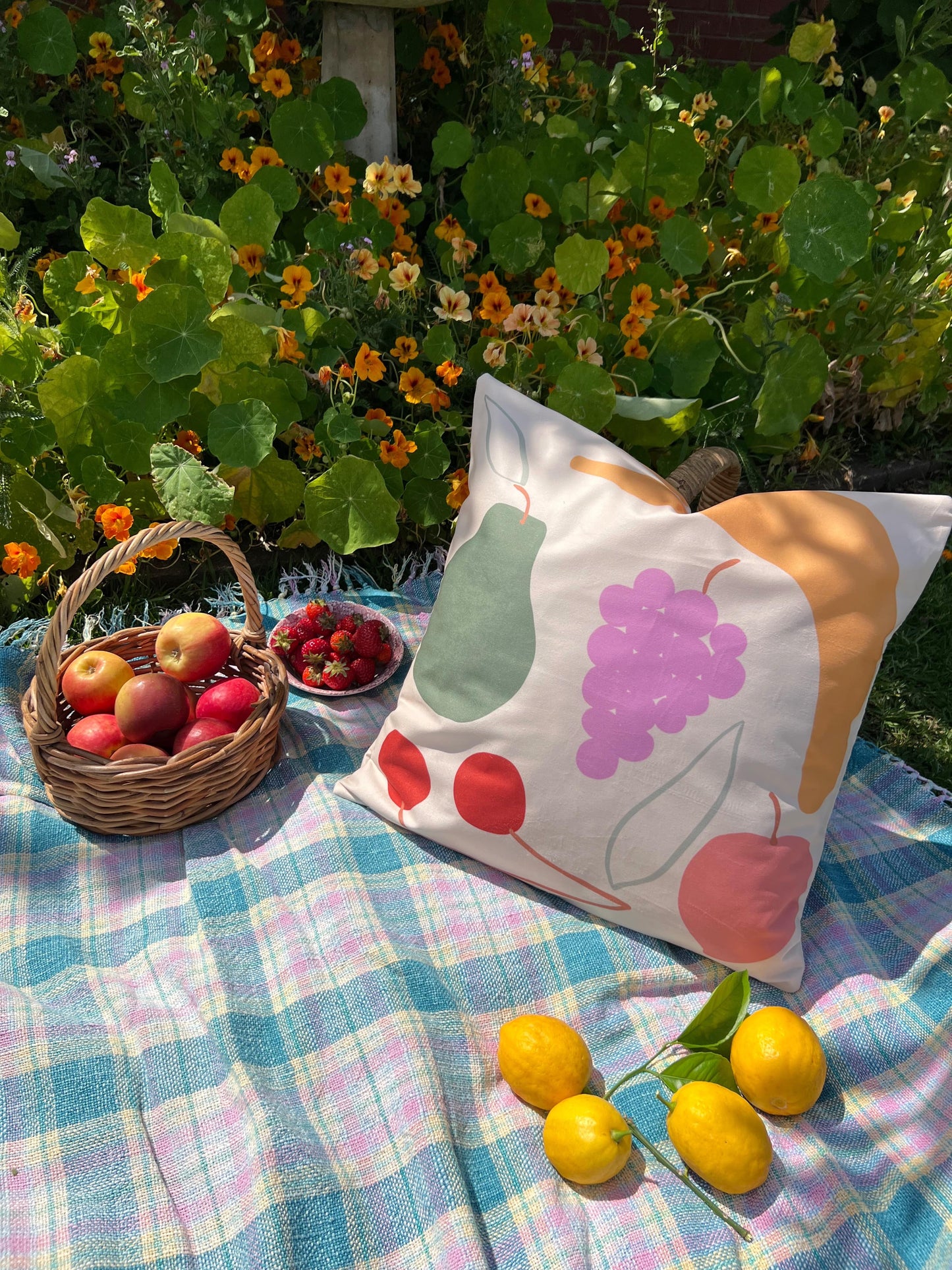fruit cushion on picnic rug surround by fruit and flowers