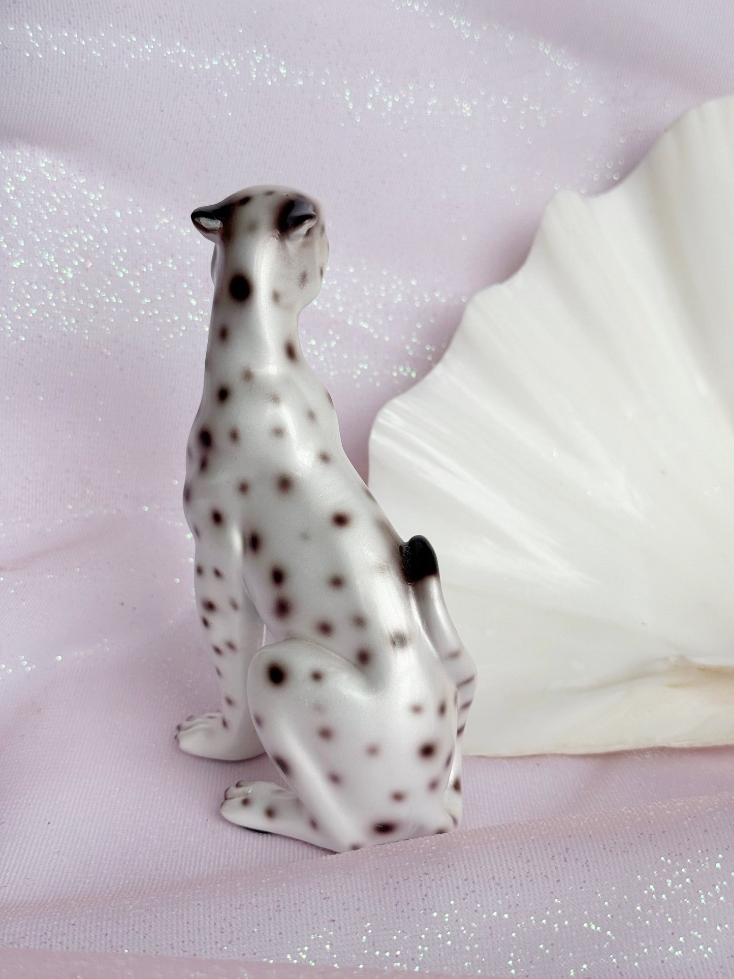 Resin figurine of a leopard with black spots on a glittery pink background