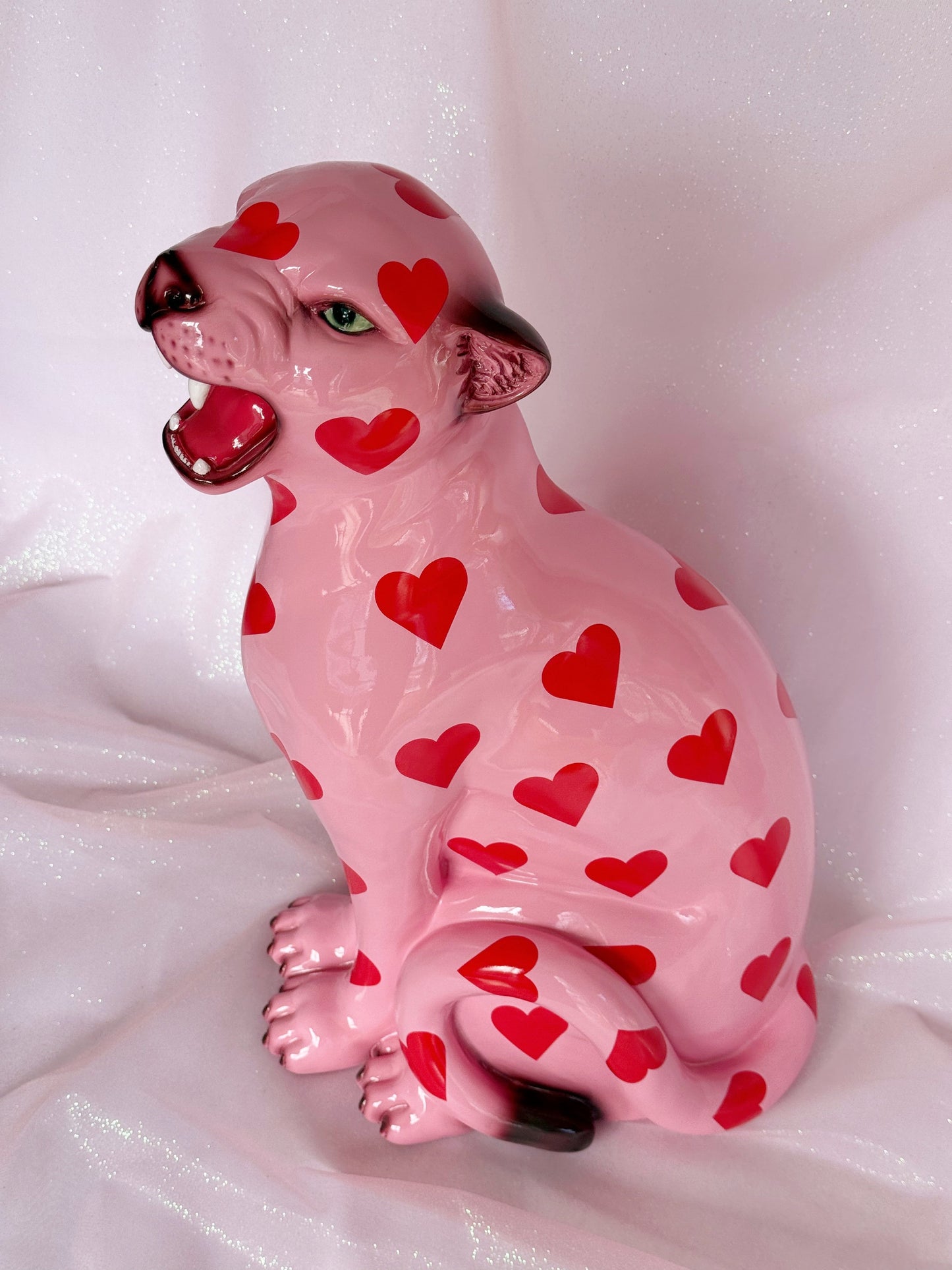 Pink ceramic leopard figurine with red heart patterns on a white background