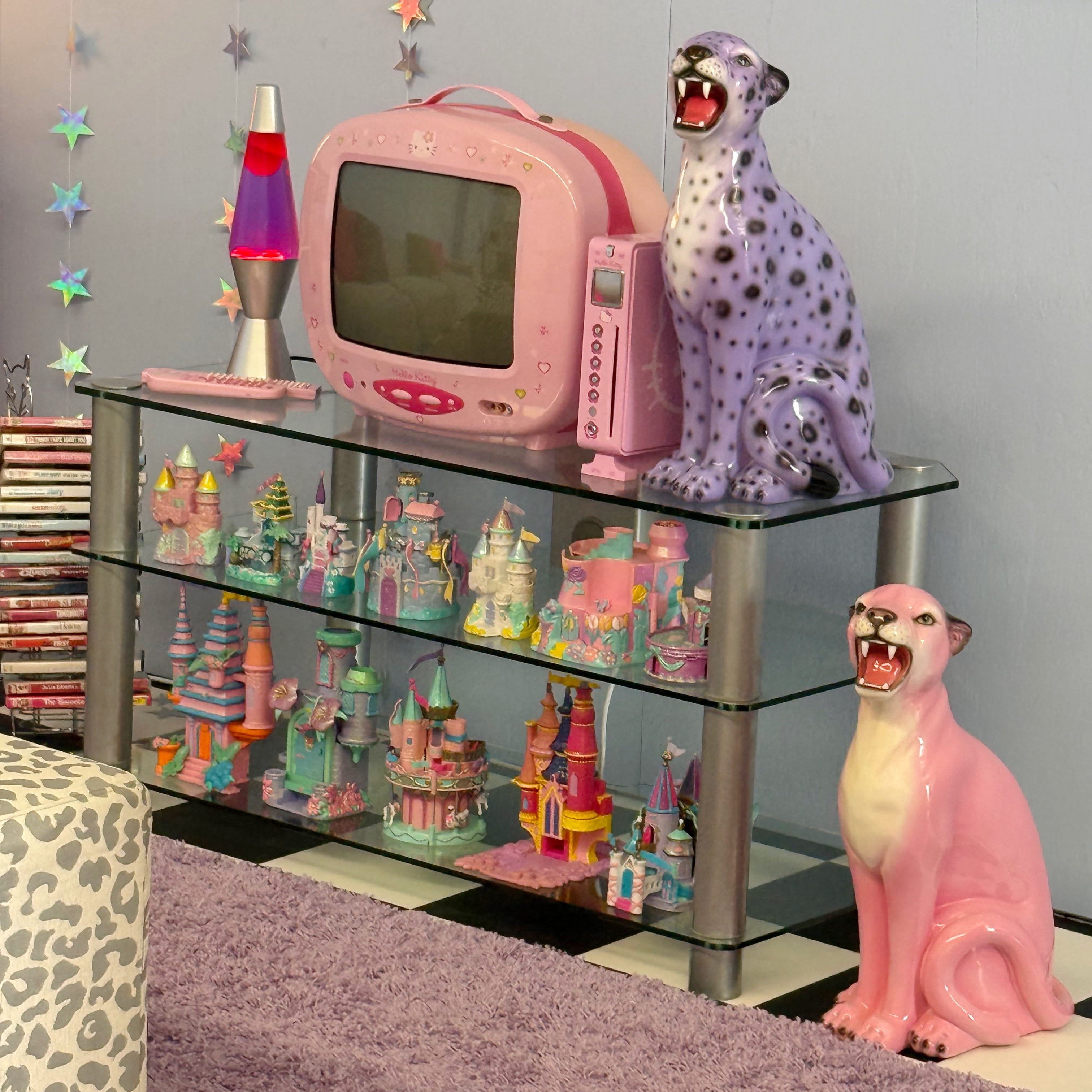 Vintage-style room with pink lava lamp, retro TV, and decorative leopard statues on a glass shelf.