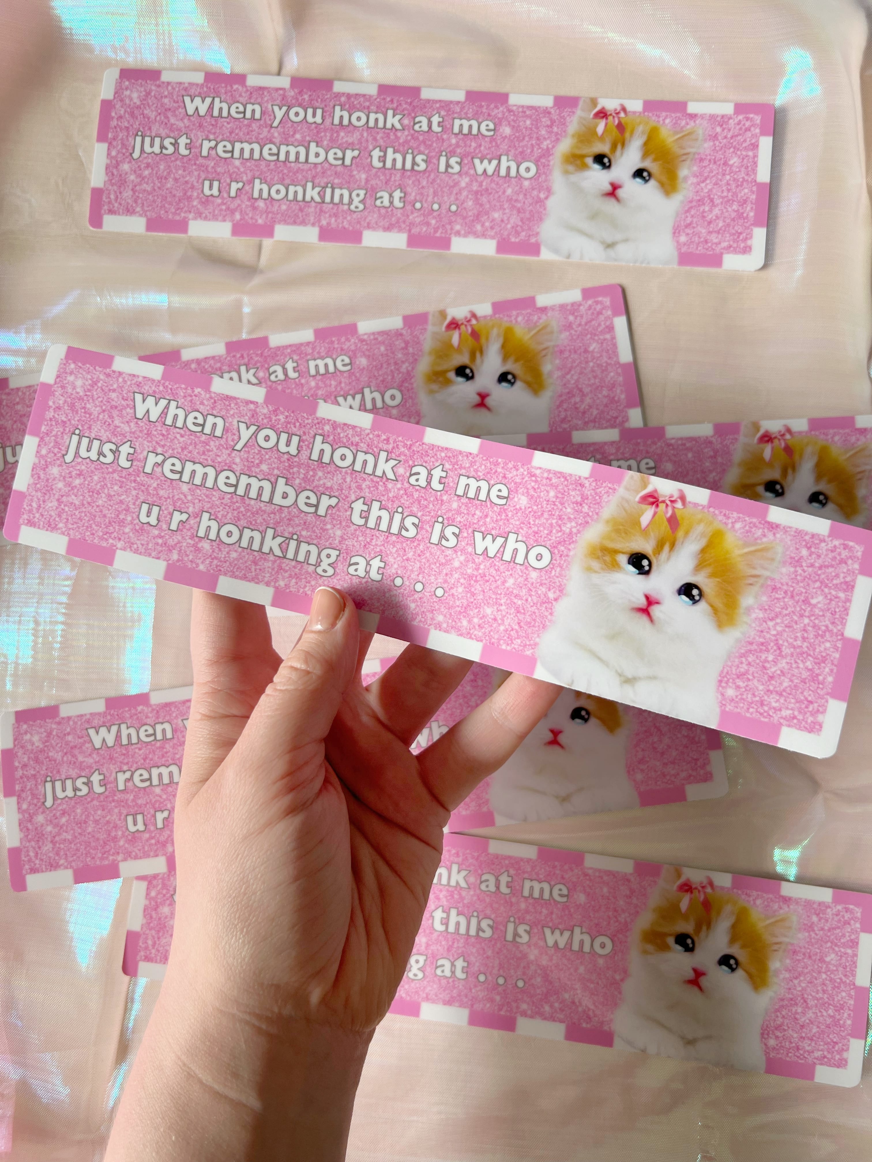  a hand holding a bumper sticker that says "when you honk at me just remember this is who u r honking at..." 