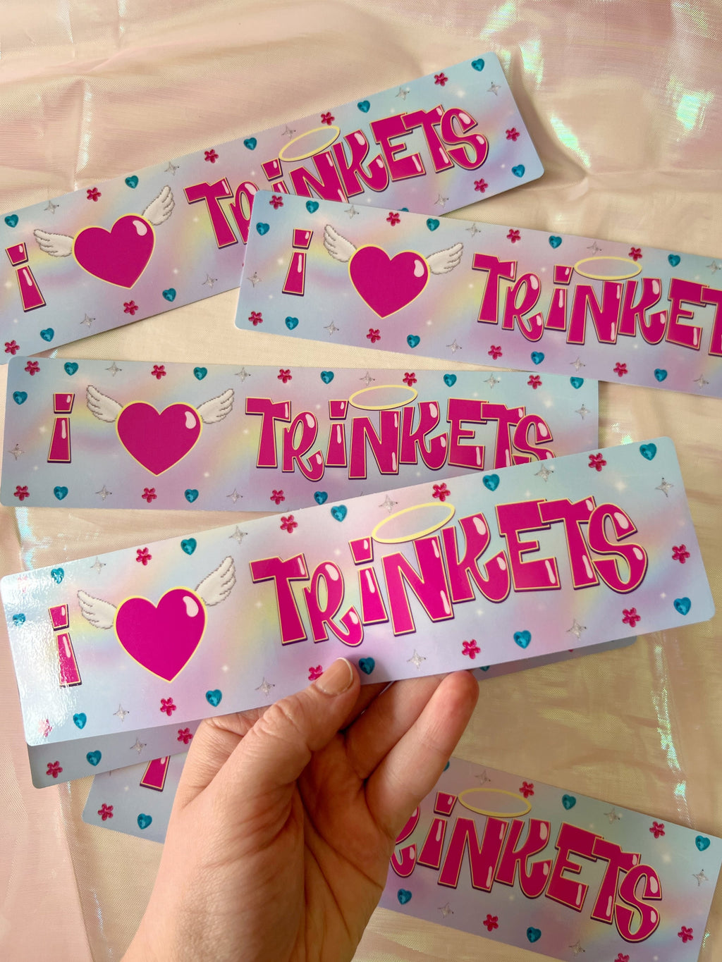 photo of a hand holding a bumper sticker that says "I love trinkets" 