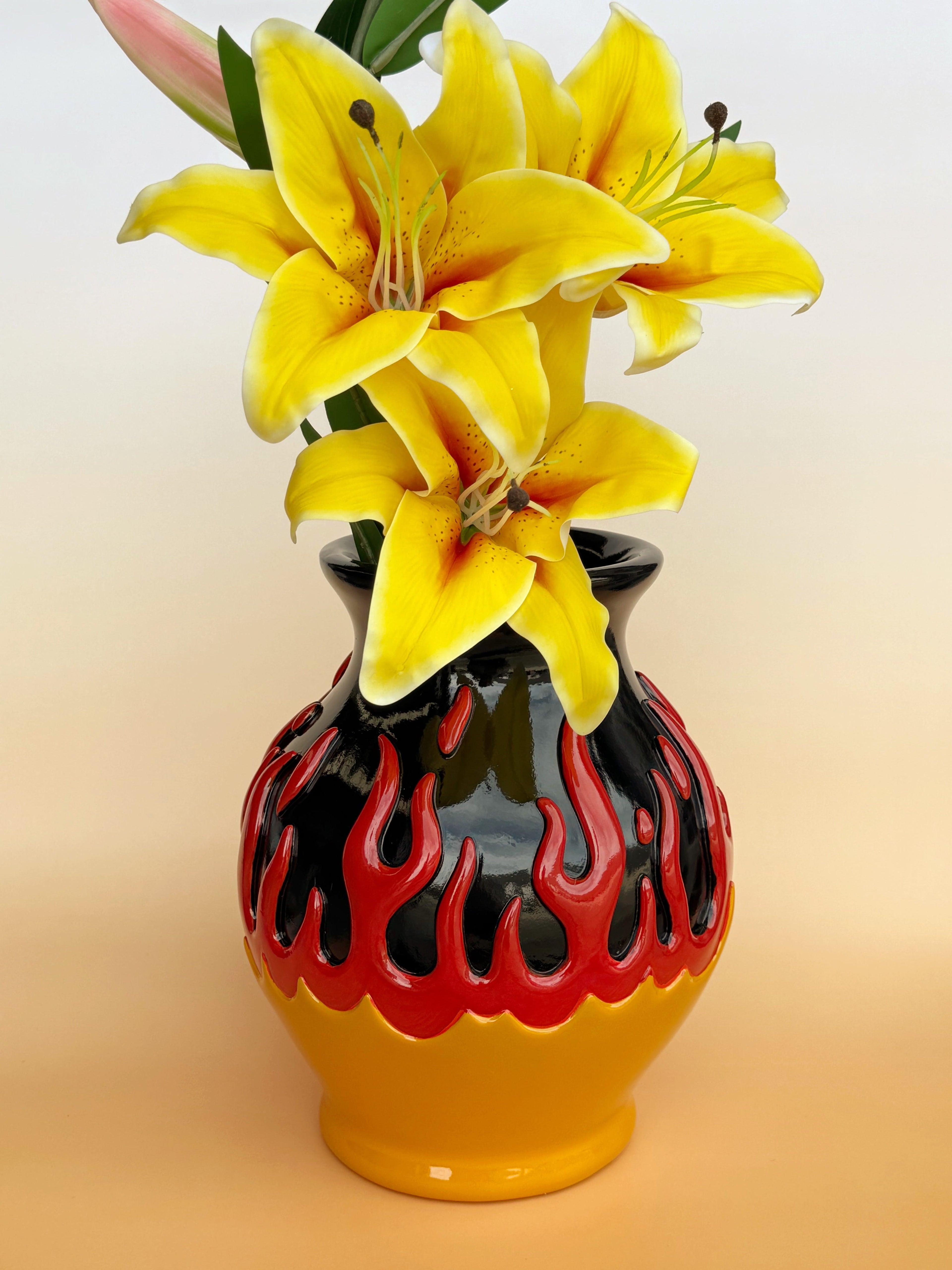 Floral arrangement in a black and red flame-patterned vase on a gradient background