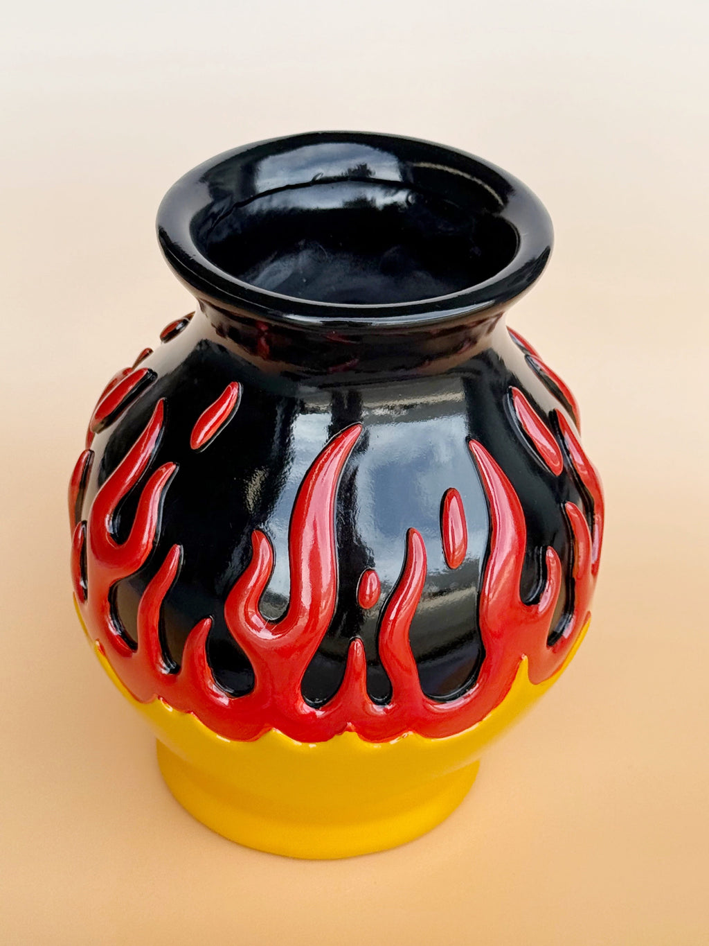 Black vase with red flame design on a beige background