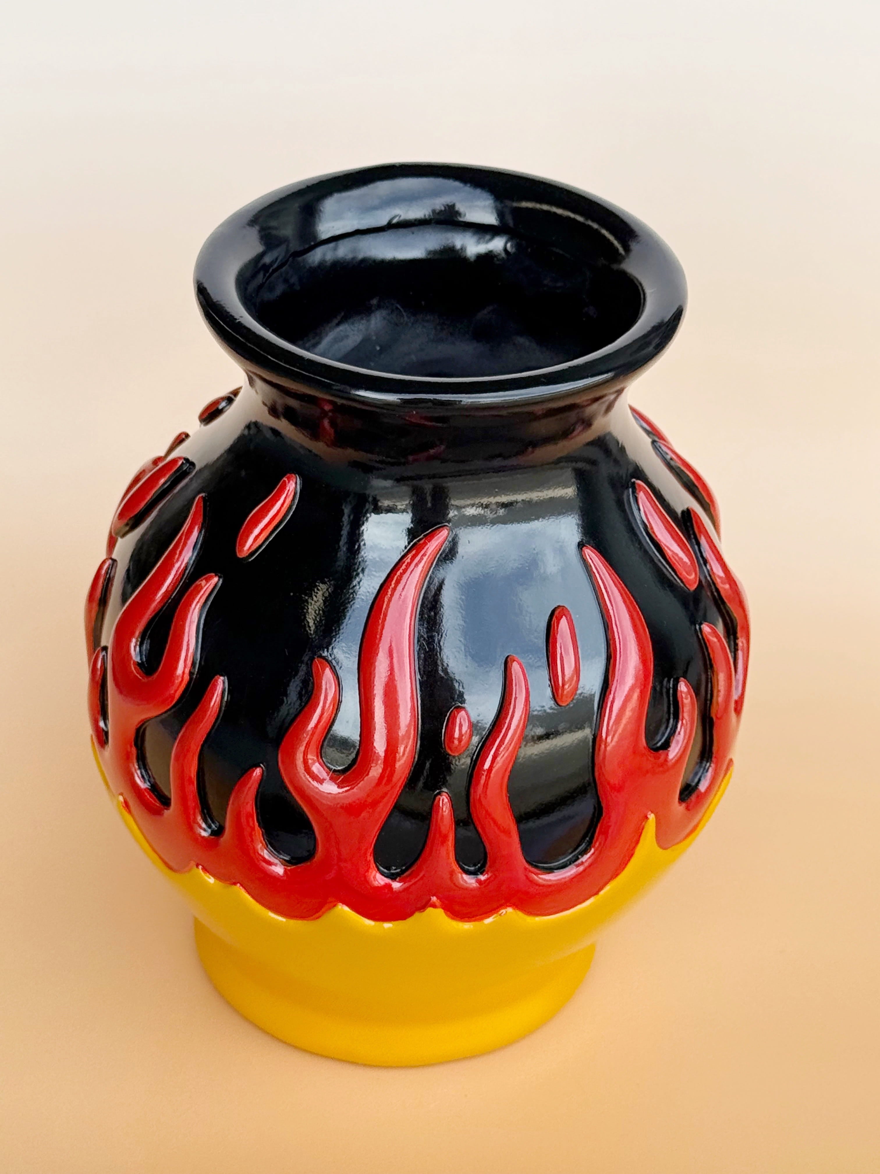 Black vase with red flame design on a beige background