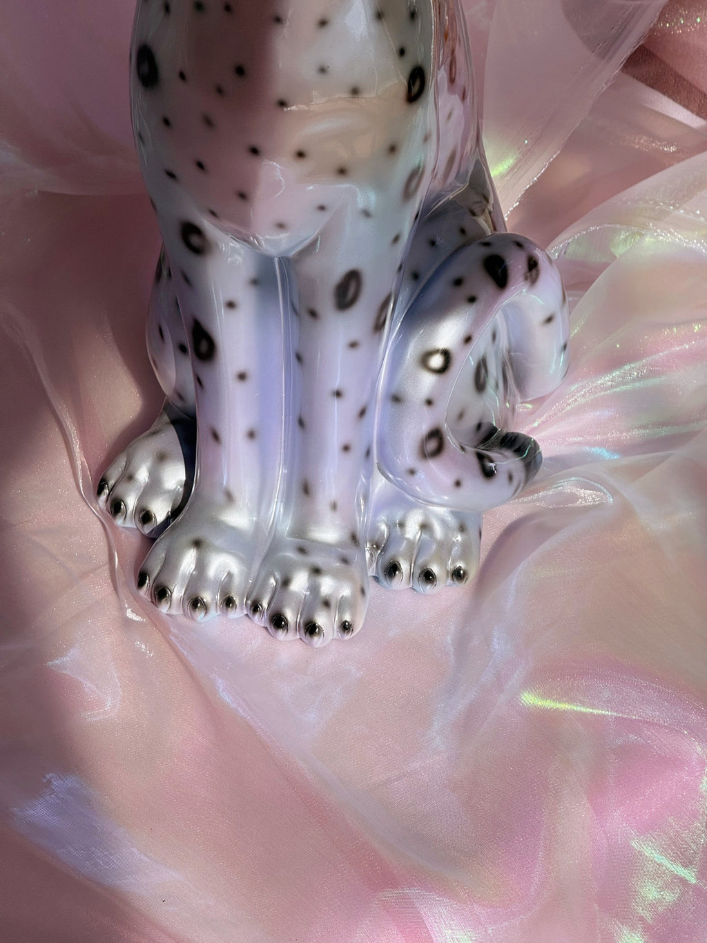 Silvery leopard figurine on a pink fabric background