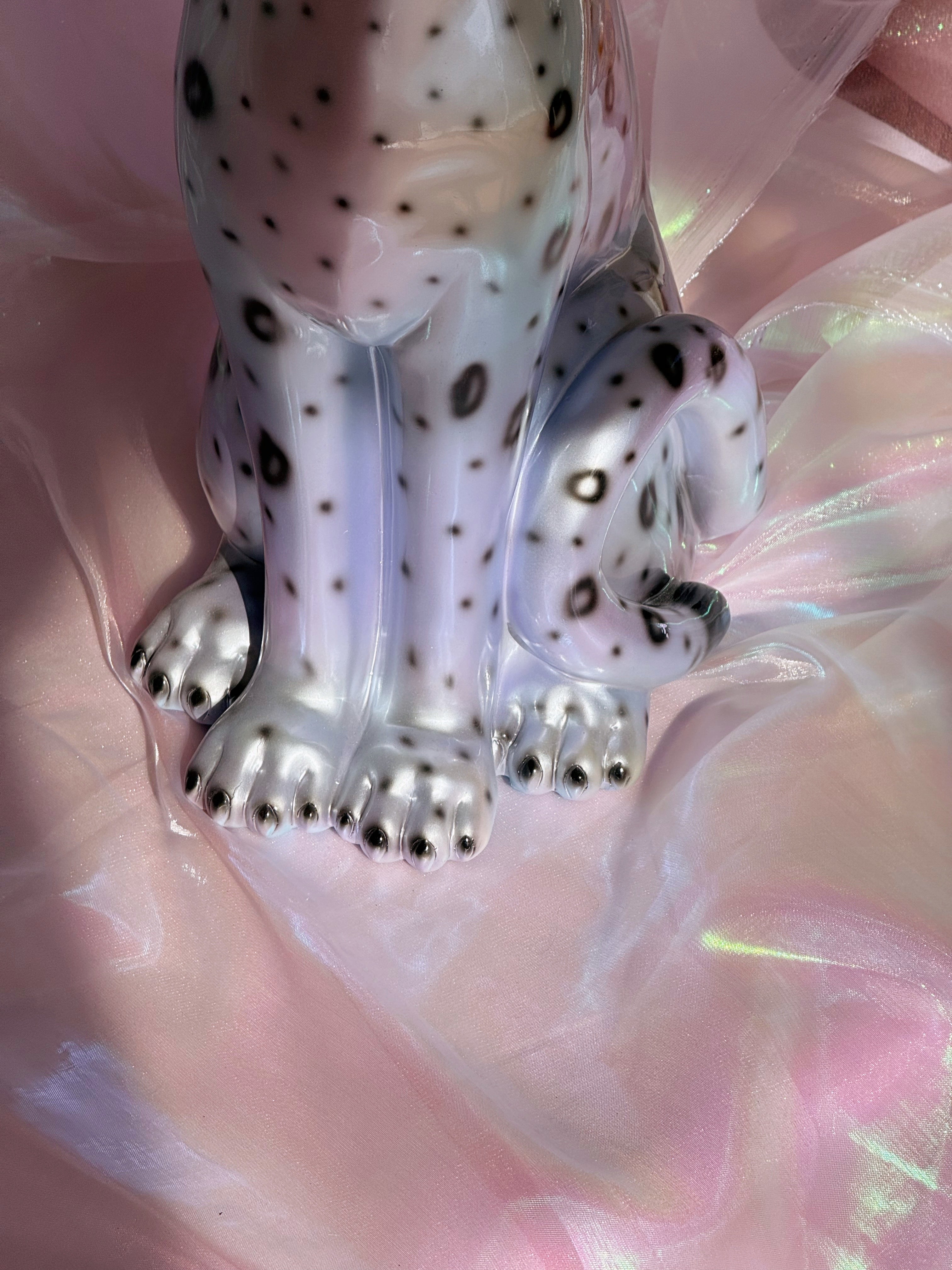 Silvery leopard figurine on a pink fabric background