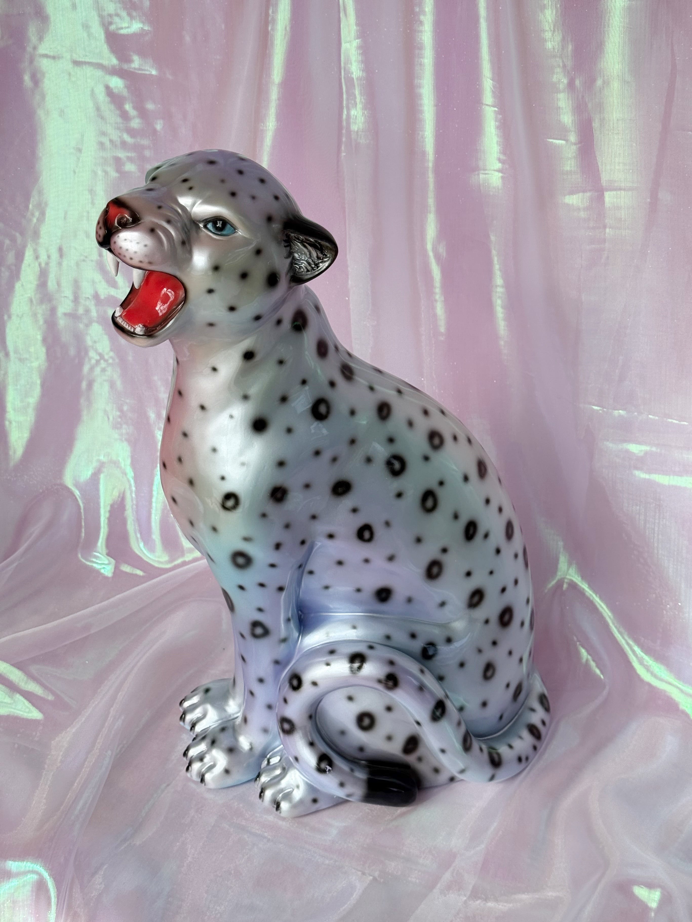 Silvery leopard figurine on a pink fabric background