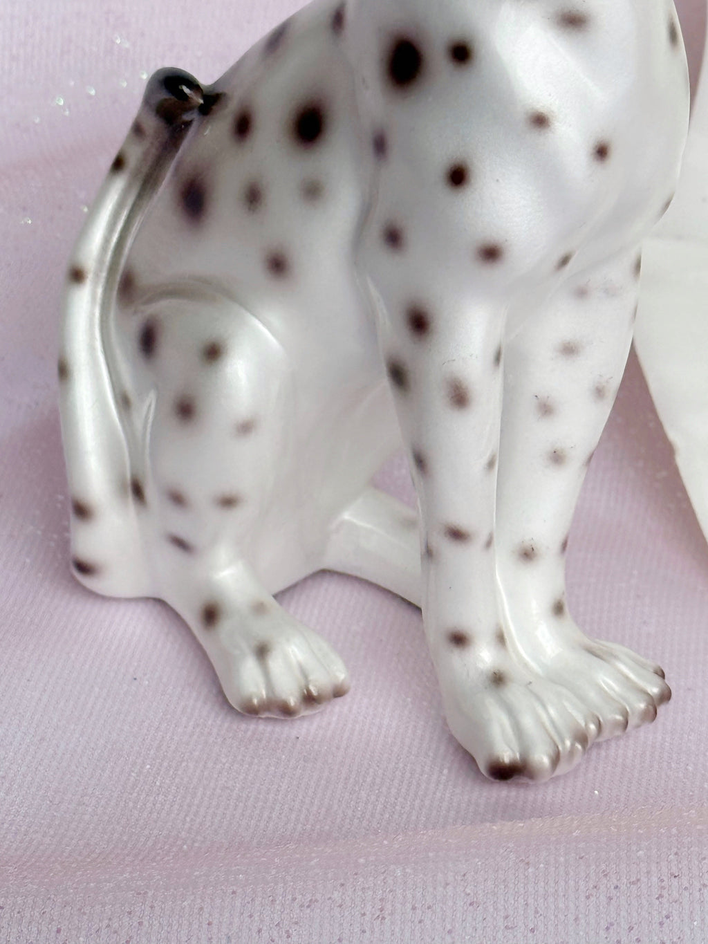 White ceramic leopard figurine with brown spots on a pink background