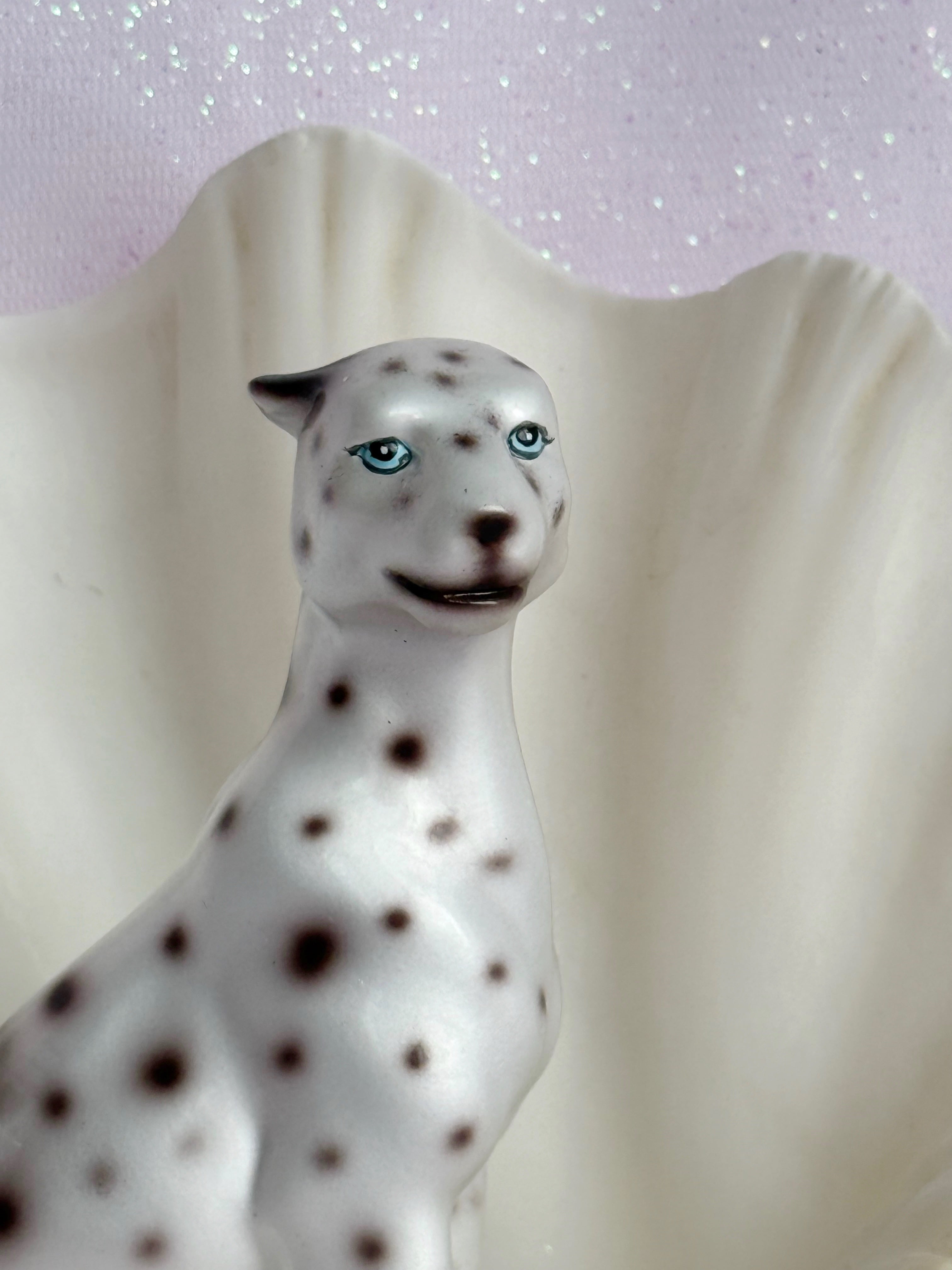 White figurine of a leopard with black spots against a light background