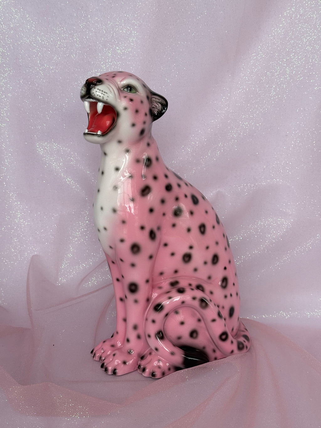Pink ceramic leopard figurine on a pink fabric background
