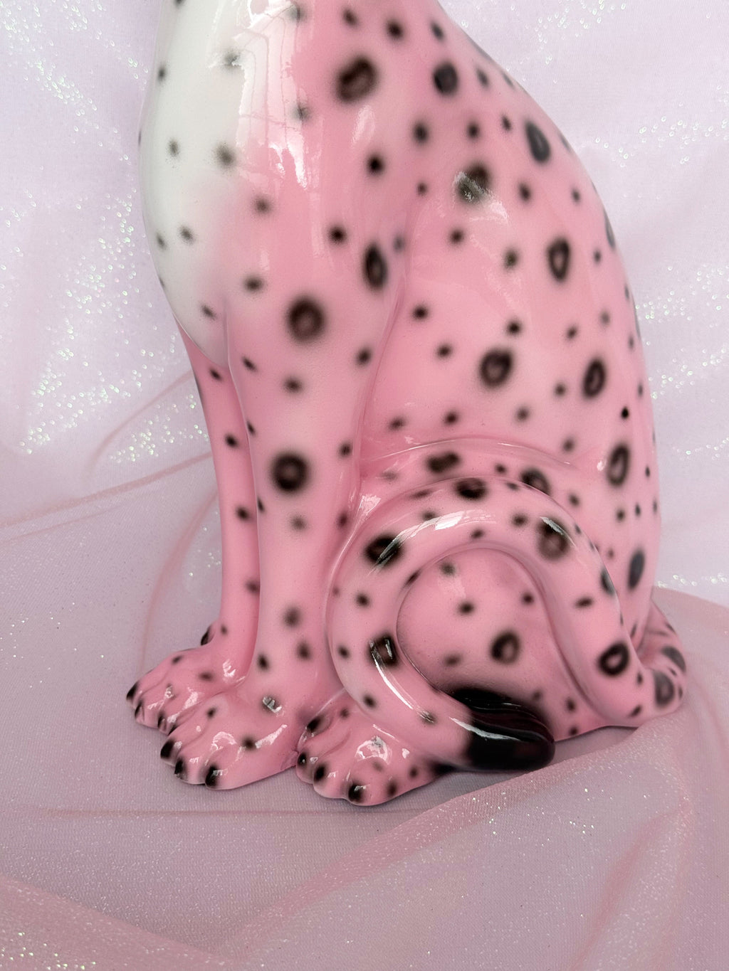 Pink ceramic leopard figurine with black spots on a light pink background