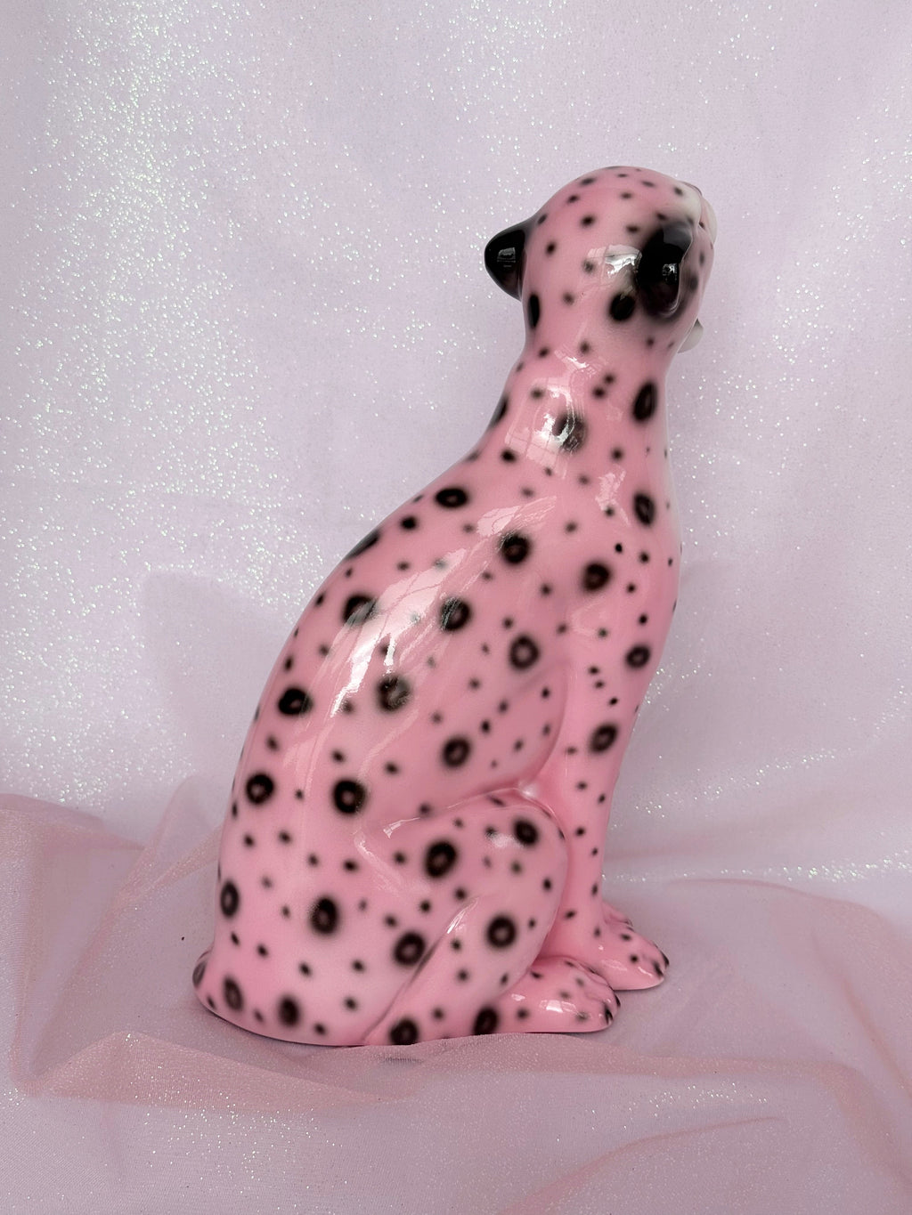 Pink ceramic leopard figurine with black spots on a white background