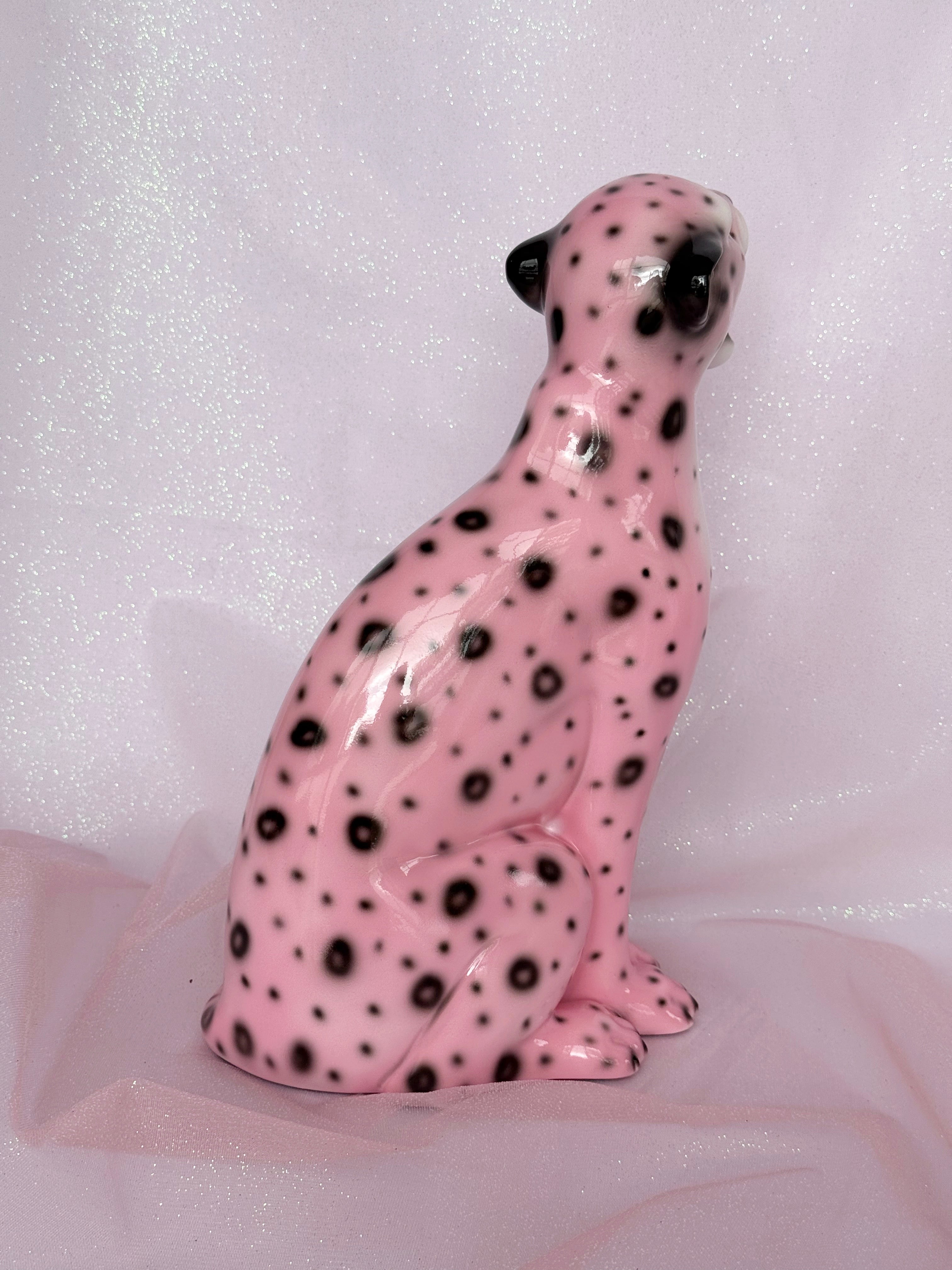 Pink ceramic leopard figurine with black spots on a white background