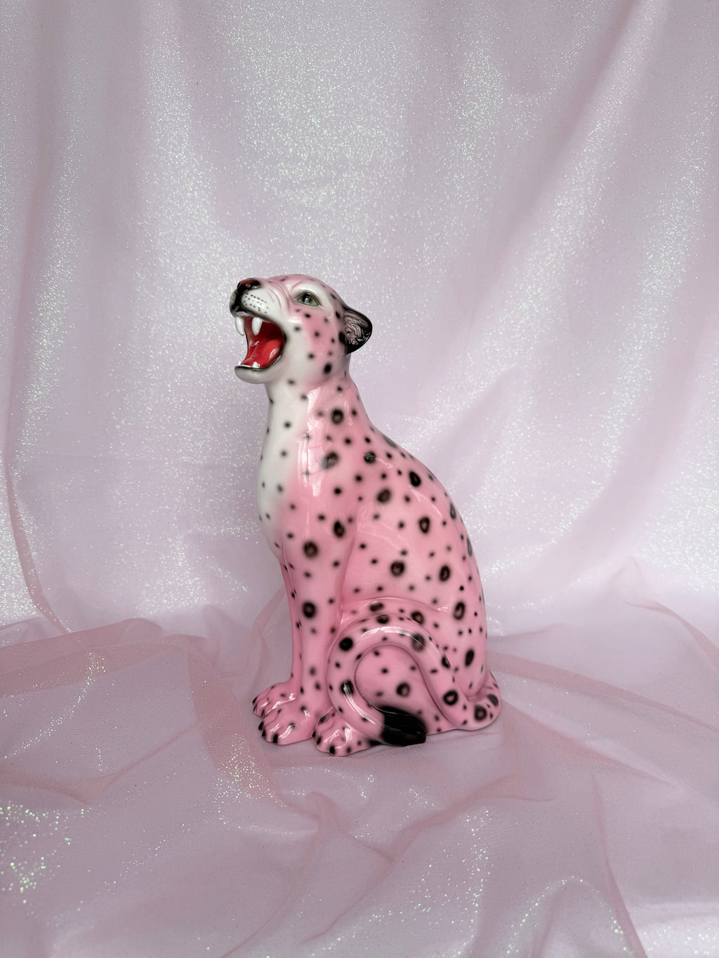 Pink ceramic leopard figurine on a light pink fabric background
