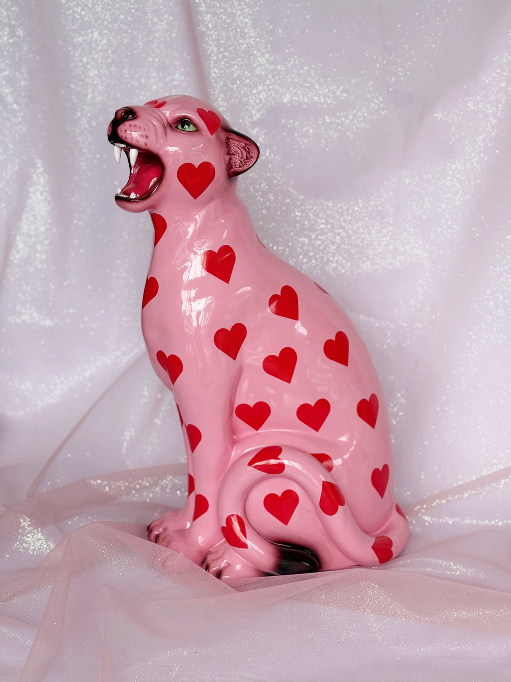 Pink leopard figurine with red heart patterns on a white background