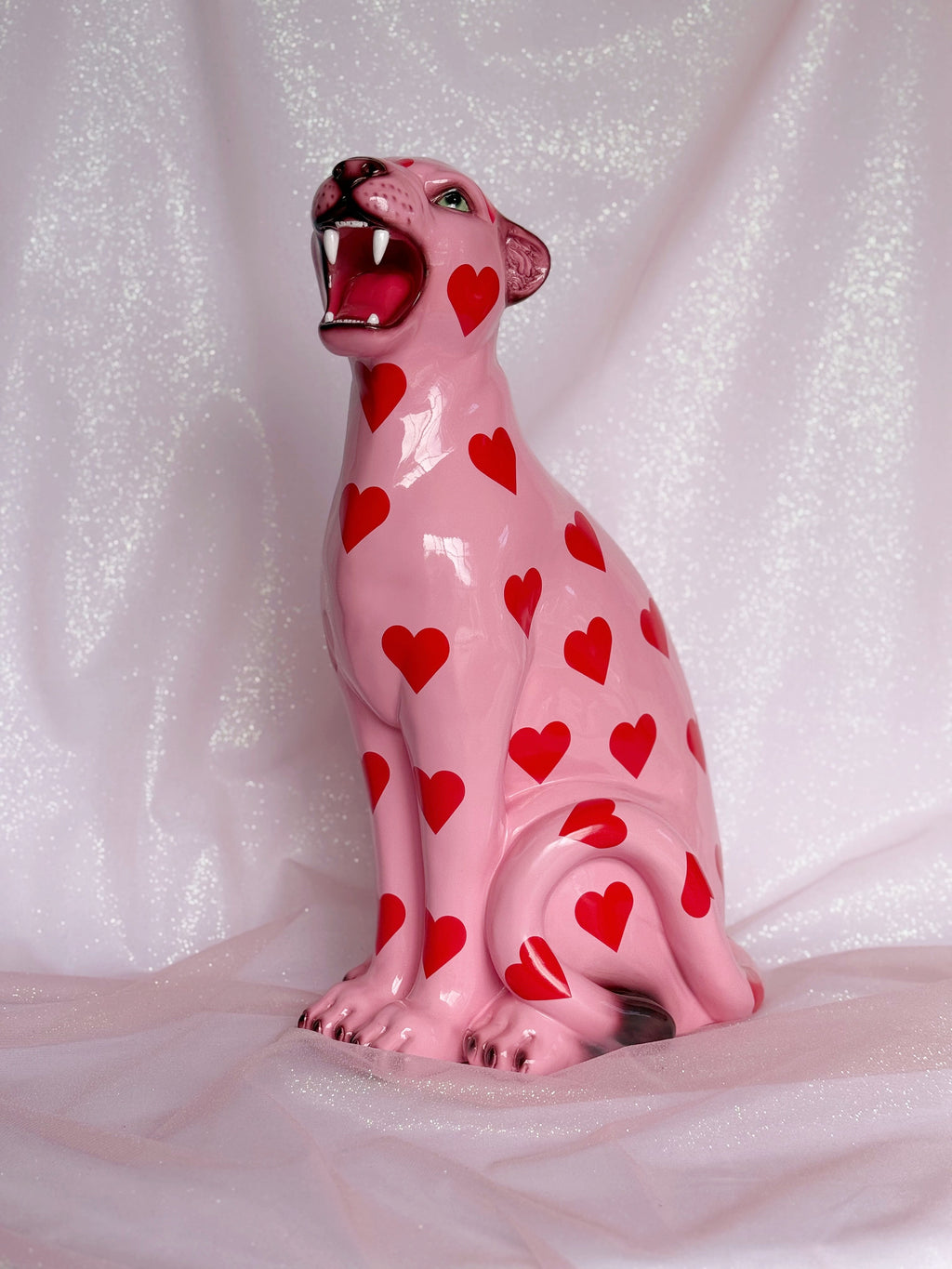 Pink leopard figurine with red heart patterns on a white background