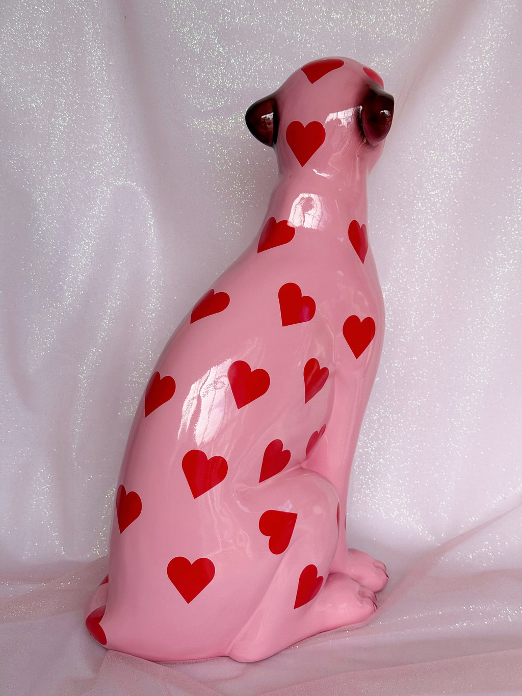 Pink ceramic leopard figurine with red heart patterns on a white background