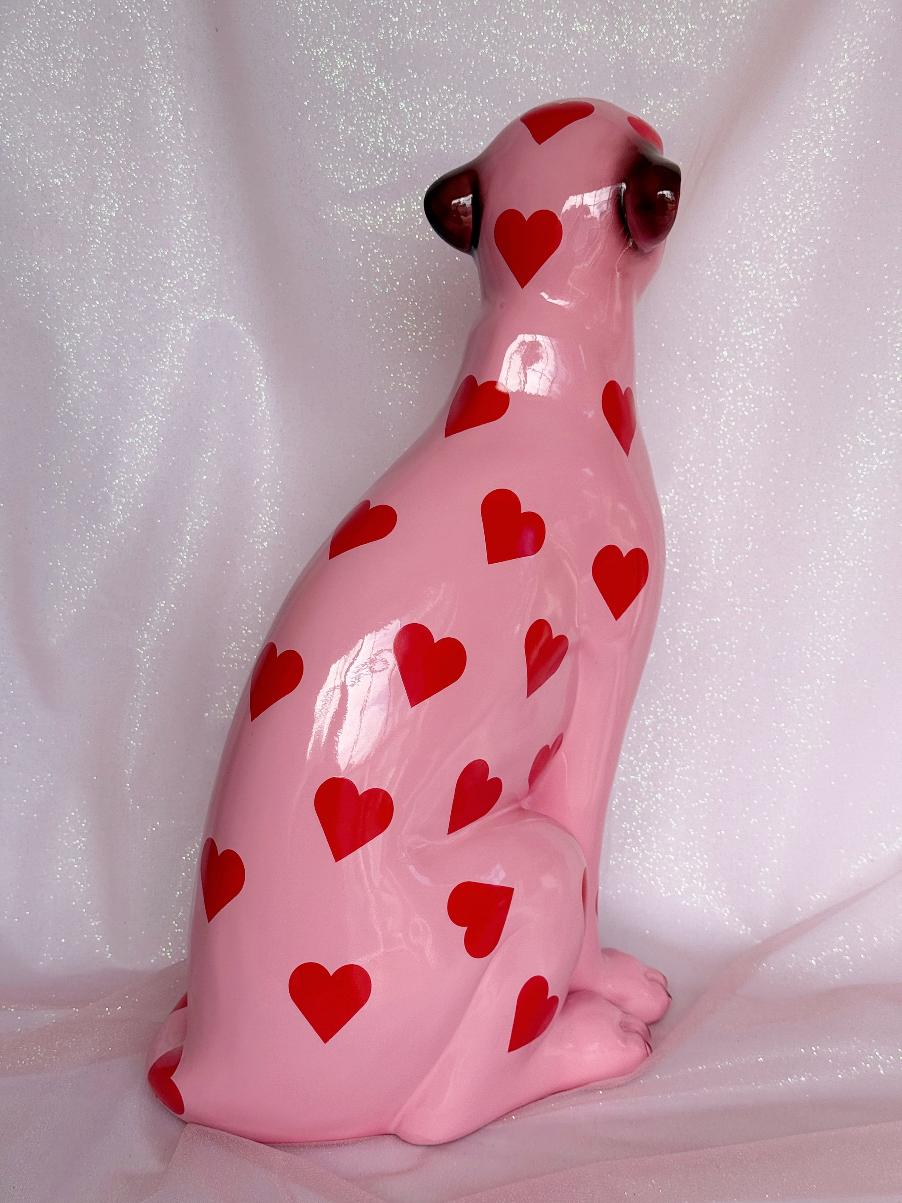 Pink ceramic leopard figurine with red heart patterns on a white background