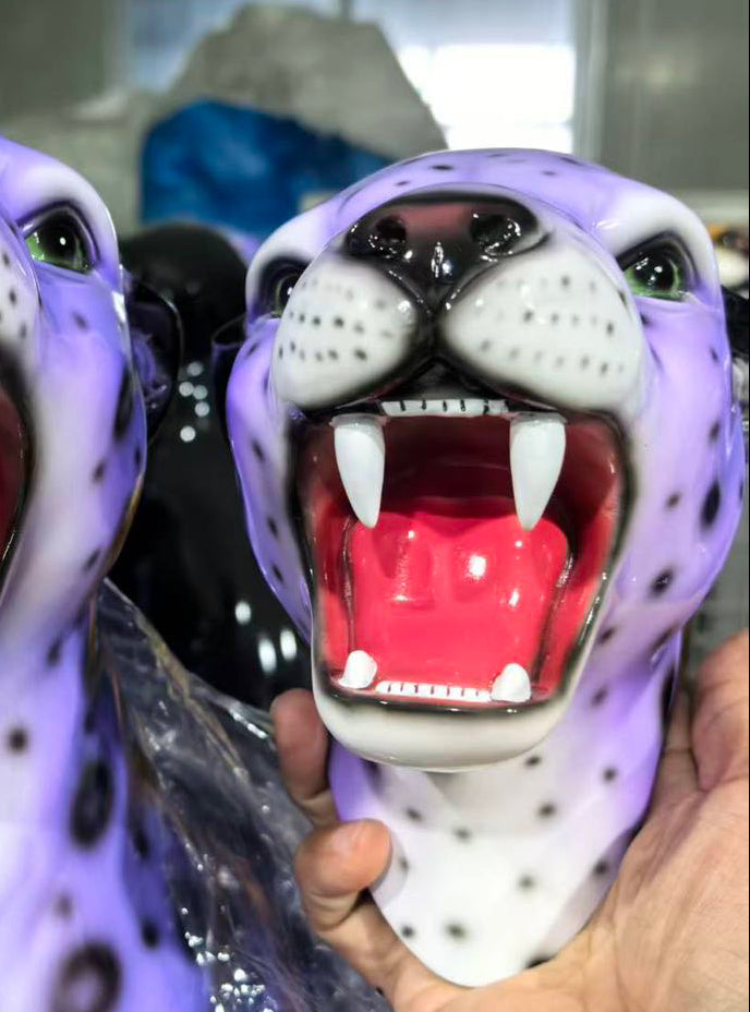 Purple panther head statues with open mouths, showing teeth, held by a hand.