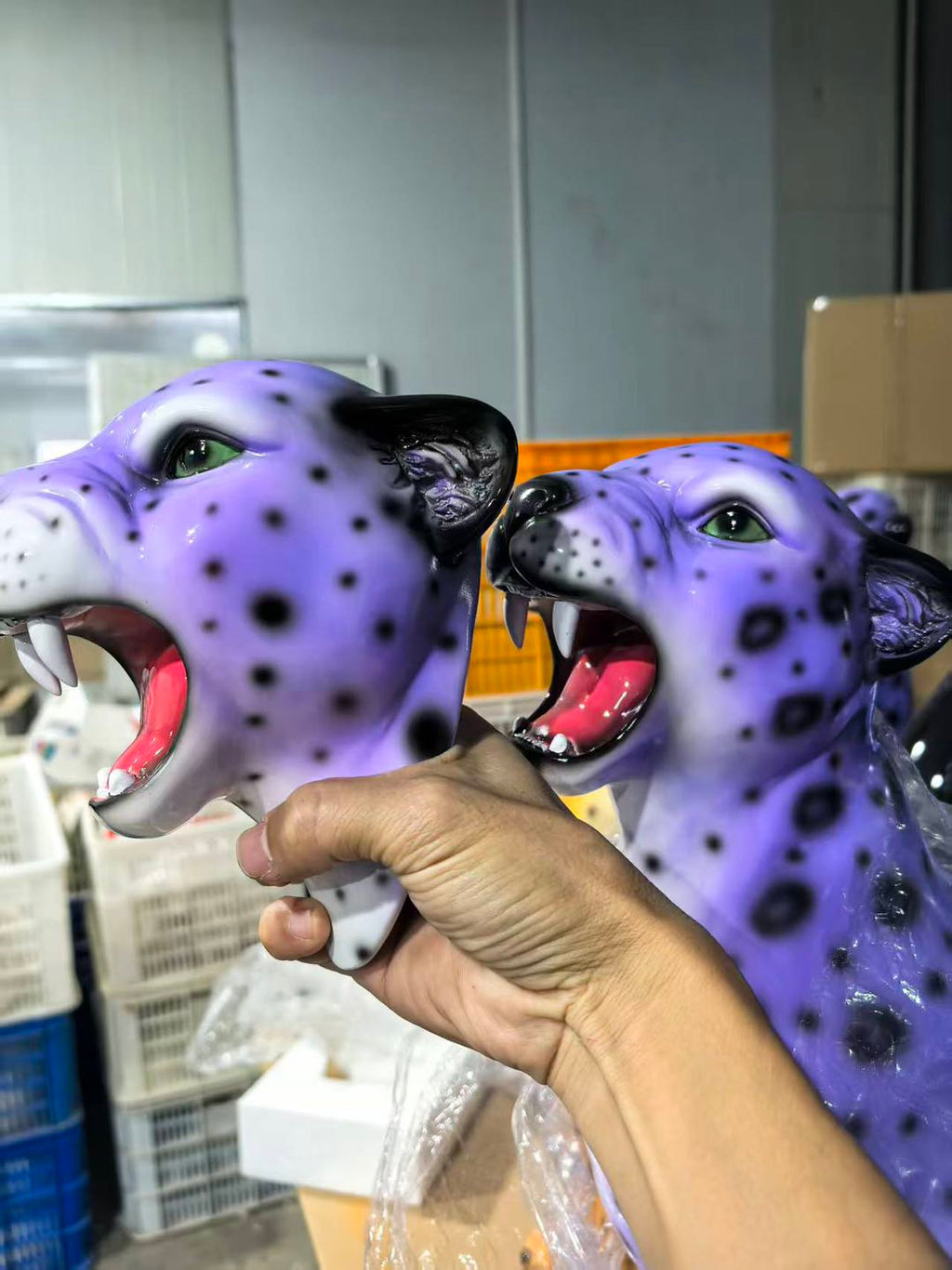 Purple leopard head figurine held by a hand in an indoor setting