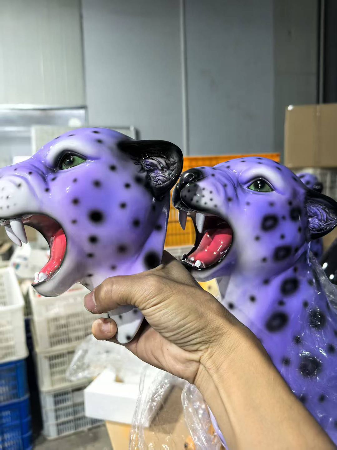 Purple leopard head figurine held by a hand in an indoor setting