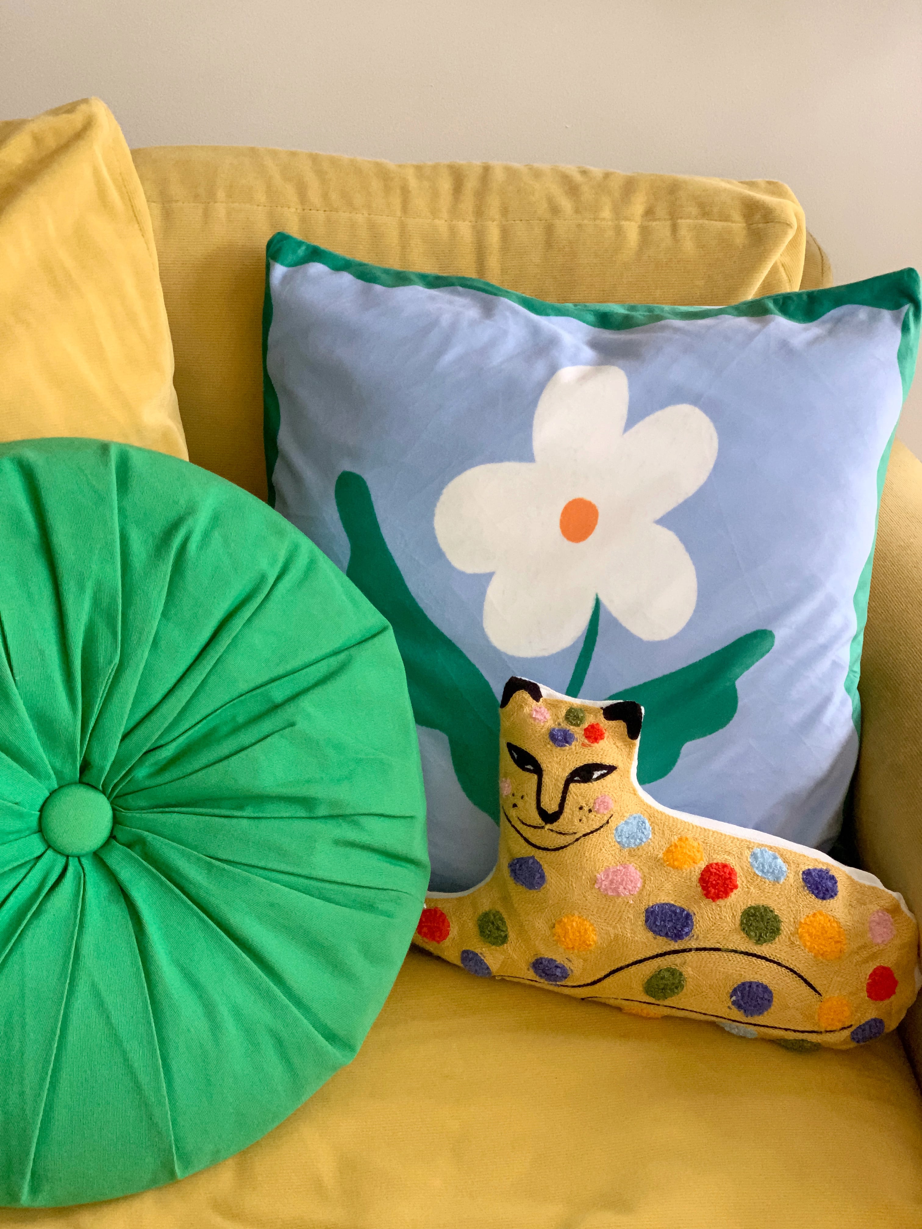 colourful leopard cushion displayed on yellow couch with other cushions